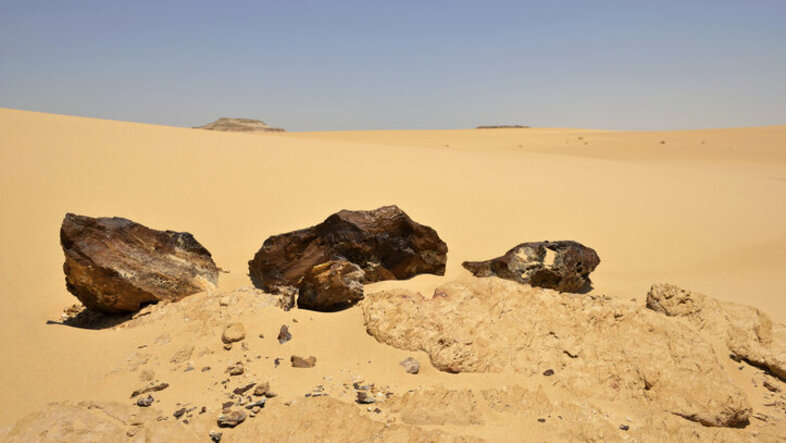 Dunkle Gesteine auf hellem Wüstensand